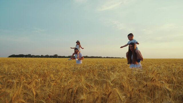 Romantic parents smiling and kissing at family picnic in wheat field, children eating snacks and watching mom and dad. Arc shot happy people spending time together. Concept of love