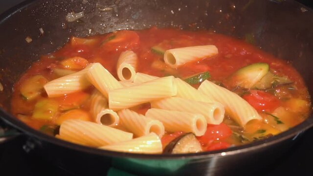 the chef adds pasta to the frying pan to the vegetables