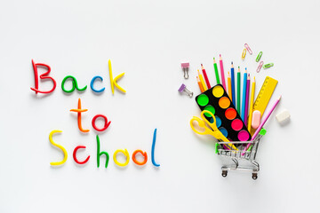Plasticine inscription "Back to school" and a cart with stationery on a white background.