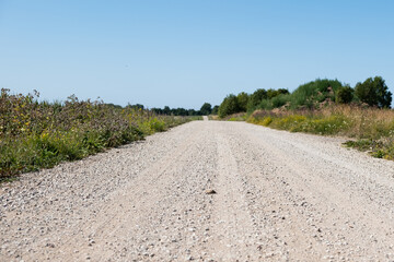 Gravel road background. Old pebble rock countryside road during summer. Empty copy space.