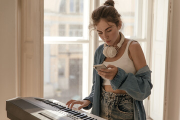 Music, instrumental, piano, hobby concept. Stylish young lady with collected hair, white top and...
