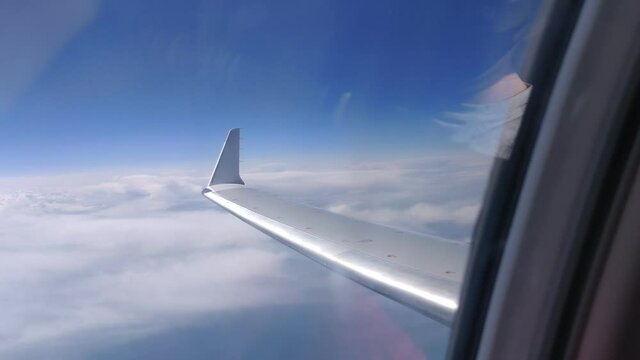 Flying airplane over clouds, Baltic sea. View trough windowFrom right to left. 2021Mitsubishi CRJ-900 LR