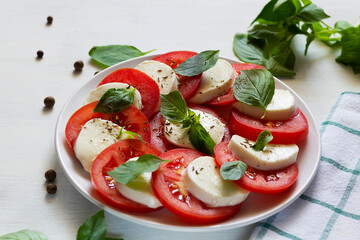 salad with tomatoes and mozzarella.Italian caprese salad. sliced tomatoes, mozzarella cheese, green basil, olive oil on a white background. fresh salad with copy space.