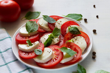 tomato and mozzarella salad.Italian caprese salad. sliced tomatoes, mozzarella cheese, green basil, olive oil on a white background. fresh salad with copy space.