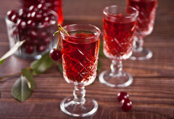 glasses of cherry brandy liqueur with ripe berries on wooden table