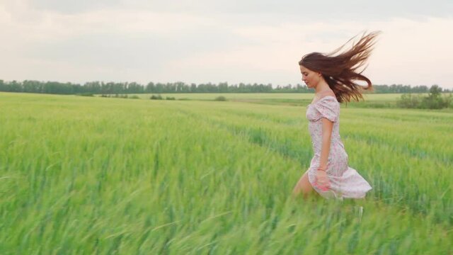Girl in a white dress in a wheat field at sunset