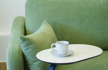 dishes for tea drinking on  side table by  green sofa.