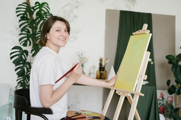 A young artist paints an abstract picture in a creative studio