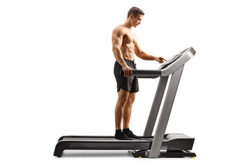 Full length profile shot of a shirtless young man setting a program on a treadmill