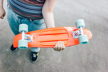 close up stylish girl carrying the penny board in the summer city