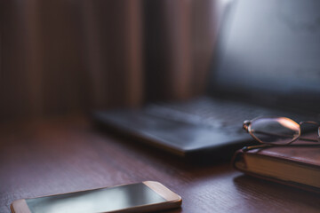 investment concept, glasses, book, phone and laptop on brown, black,  background. Business, investment, income concept, vintage style