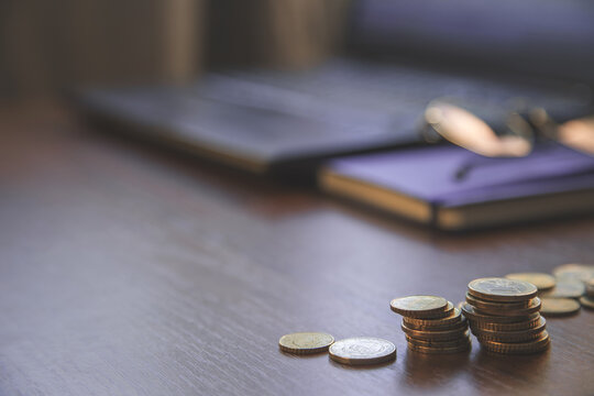 investment concept, glasses, book, coins  and laptop on brown, black,  background. Business, investment, income concept, vintage style