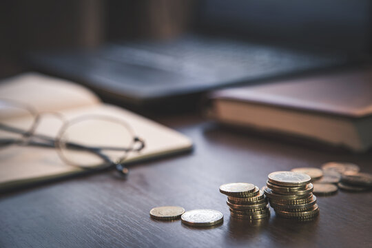 investment concept, glasses, book, coins and laptop on brown, black,  background. Business, investment, income concept, vintage style - Powered by Adobe