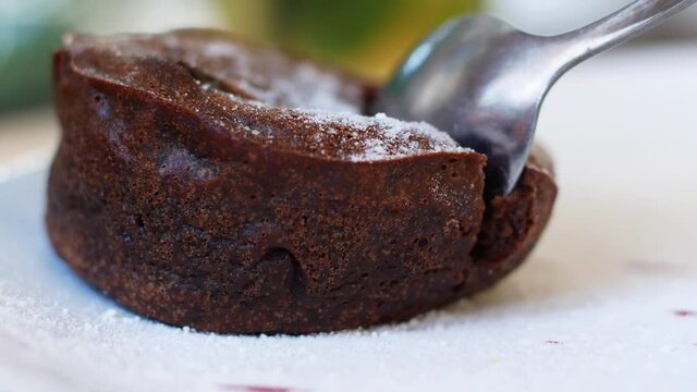 Women eating chocolate cake in a summer cafe. Liquid chocolate flows smoothly out of the cake, close-up. Food, dessert.
