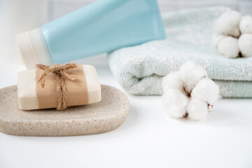 Bathroom table with new soap bar on tray, fresh clean towel and tube of cosmetics onit decorated with fluffy cotton balls.
