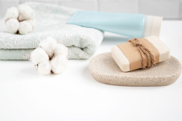 Bathroom table with new soap bar on tray and fresh clean towel decorated with fluffy cotton balls