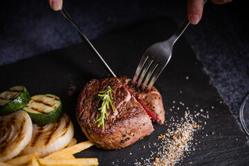 cutting tenderloin beef steak with knife and fork