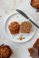 Halved muffin with walnuts on a white plate with a knife. Light background. 