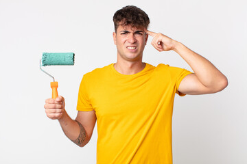 young handsome man feeling confused and puzzled, showing you are insane. painting home concept