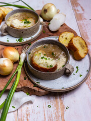 French cuisine onion soup in a ceramic cup with croutons on a light background