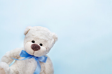Partial view of white teddy bear on light blue background with clouds. Greeting card, baby shower invitation, baby birth, gender reveal concept. 