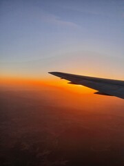 View of the sky and the wing with the iluminator of the aircraft. Lovely sunset, mountains and atmosphere of travel.