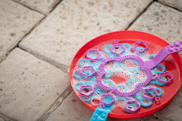 A close-up of a bowl and bubble blower against the backdrop of paving slabs. Selective focus