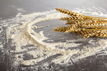 Fototapeta na wymiar background from flour on a dark table, ears, pastries, bread. flour texture closeup