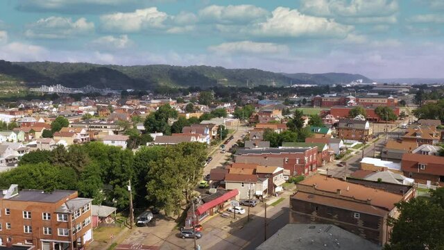 A morning forward aerial view of Ambridge, a small working class river town in Western Pennsylvania. Tilt up to summer time lapse cloudscape. Pittsburgh suburbs.	