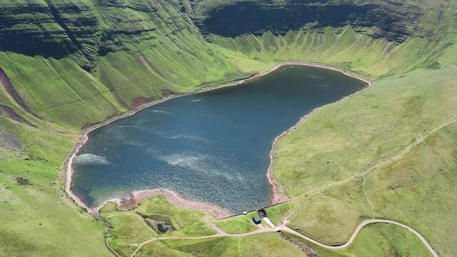 Aerial view of a lake at the foot of large cliffs (Llyn y Fan Fach)