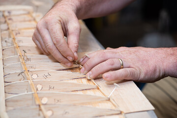 Working hands building balsa wood airplane model wing