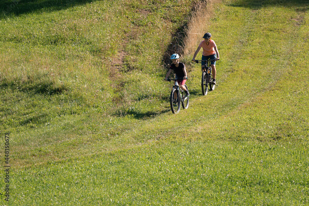 Wall mural Two girls on mtb bikes. Mother and daughter riding on a trail.