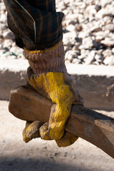 gloved hand holding the handle of a wheelbarrow