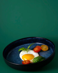 Scrambled eggs with tomatoes and basil lies on a blue plate, healthy breakfast
