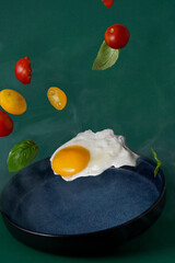 Scrambled eggs with tomatoes and basil flying on a blue plate, food levitation