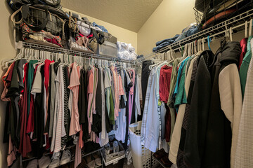 Small full walk in closet with two hanging rods and shoe racks below