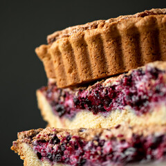 Sweet pie with red berry filling. Side view. Sweet pastries, dessert on black background. Close-up shot. Square format. Soft focus.