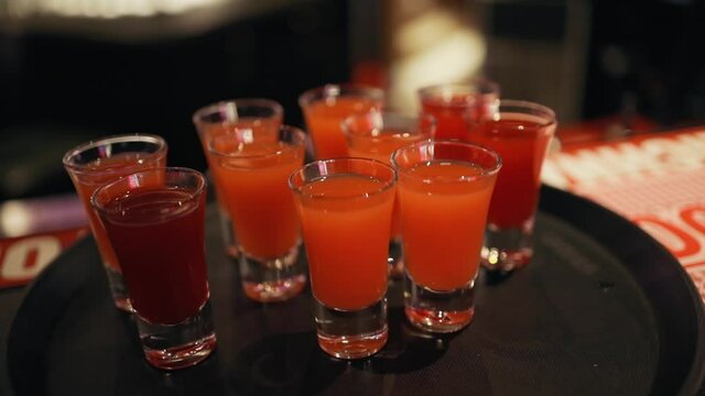 Dolly out of bunch red or orange shots at bar counter in pub