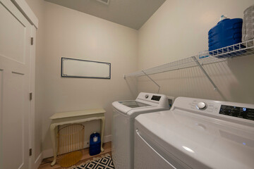 Laundry room interior with top load appliances and wire shelving unit