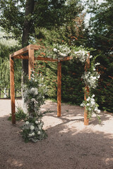 Fototapeta na wymiar Wedding arch on boho style with white flowers in park.