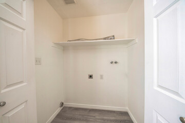 Empty laundry room interior with electrical socket and wall mounted faucet