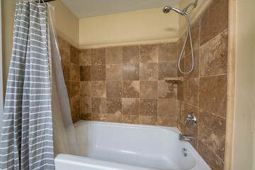 Bathtub inside a bathroom with brown tiles wall surround