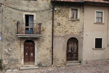 Fototapeta na wymiar Old Stone House Facades with Wooden Doors, Windows and Iron Balcony in Central Italy