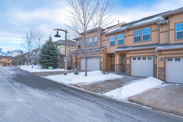 Townhouses exterior with attached garage and a driveway cleared of snow