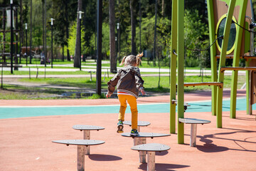 little girl jumping on the simulator on the obstacle course in the playground
