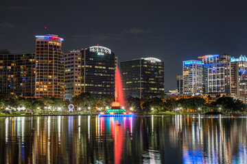 Fototapeta na wymiar Nightime photo of Lake Eola in downtown Orlando with the colorful fountain and reflections on the water