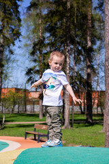 Fototapeta premium little boy walks through the territory of the playground outdoors on sunny day.