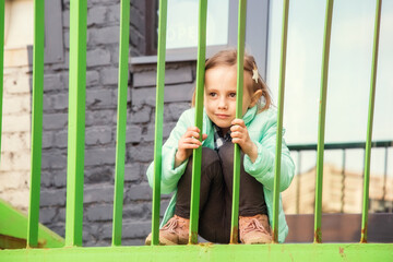Adorable little girl sitting with a bored face on the iron staircase