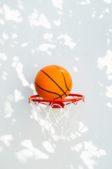 Basketball hoop on a white wall. The ball about to enter the ring.