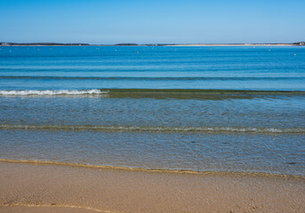 Seascape with flat waves rolling in on the shallow sea water